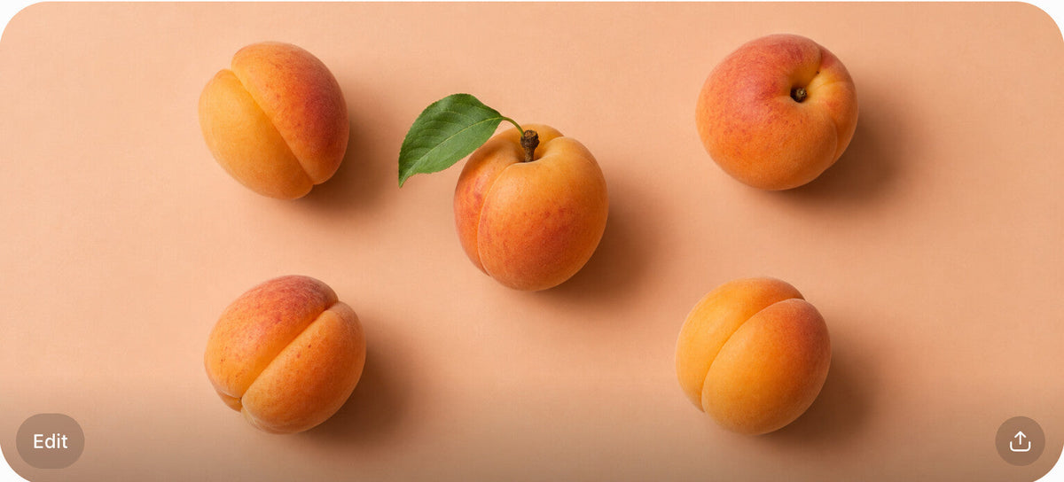 Five ripe apricots scattered in an overhead flat-lay on a peach surface