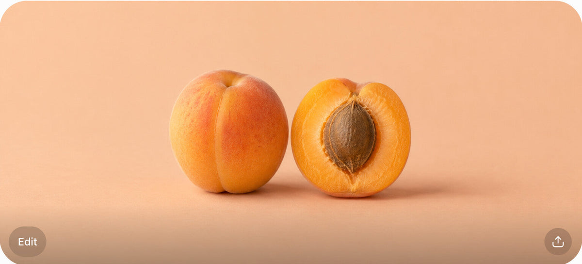 One whole and one halved apricot centered on a peach-colored surface