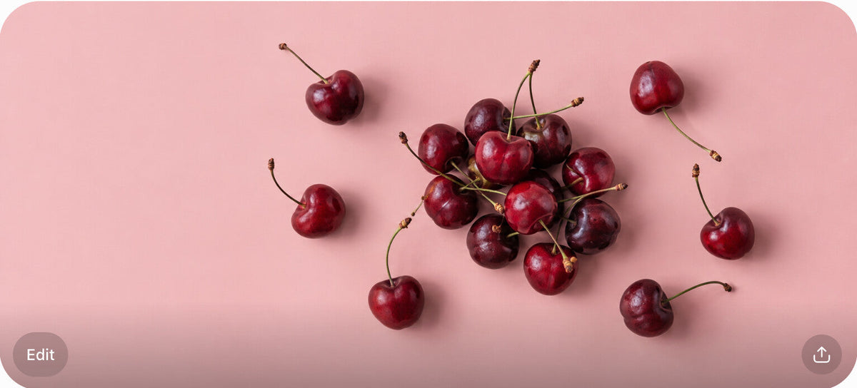 A loose pile of fresh cherries with scattered single cherries on a blush surface