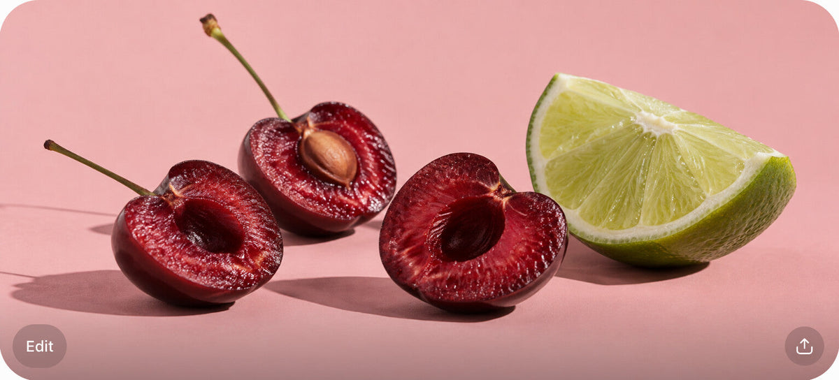 Three halved cherries and a lime wedge on a blush surface with high-contrast side light