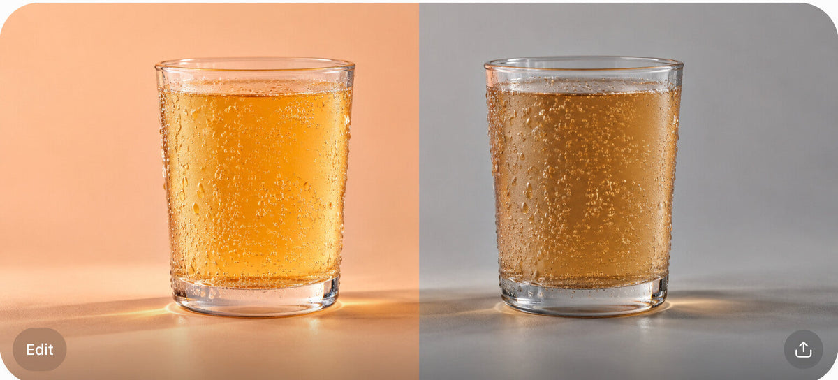 Two glasses of soda, one golden amber and one muted golden-brown, split on a peach and gray surface