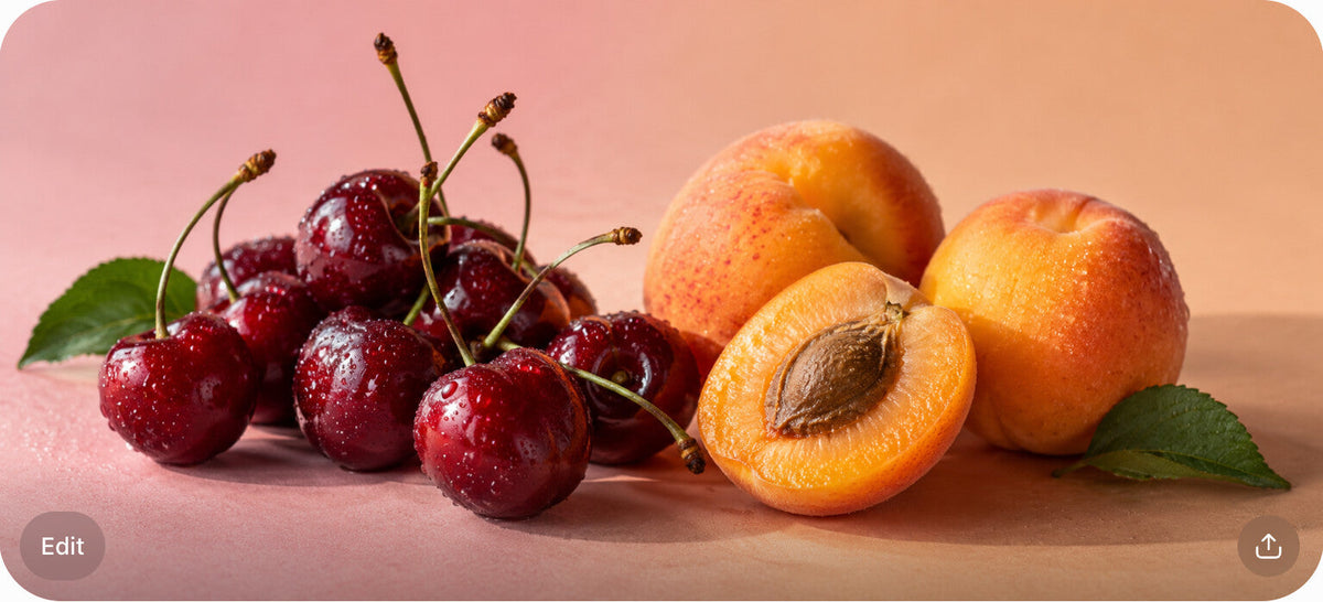 A cluster of fresh sour cherries and whole and halved apricots on a blush-to-peach surface