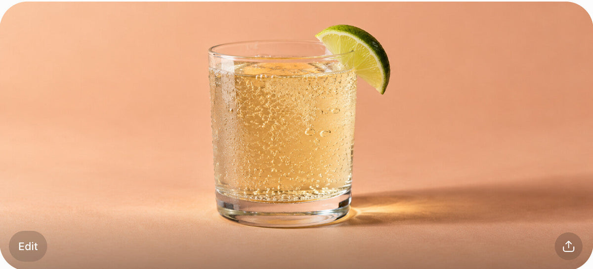 A glass of pale golden clear soda with a lime wedge on the rim