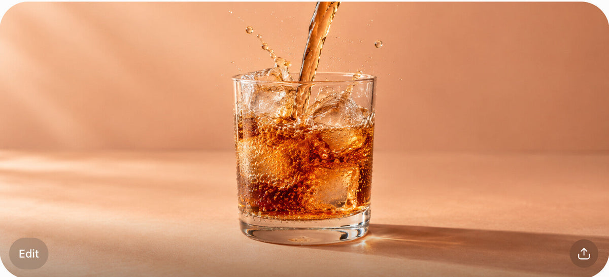 Amber tart soda pouring and splashing into a glass with ice