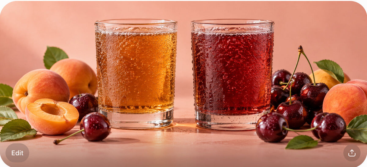 Two glasses of tart craft soda, amber and sour-cherry red, surrounded by fresh cherries and apricots