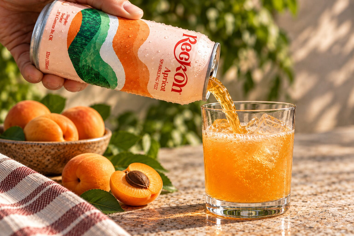 Reckon Apricot poured into a glass over ice with fresh apricots, outdoors