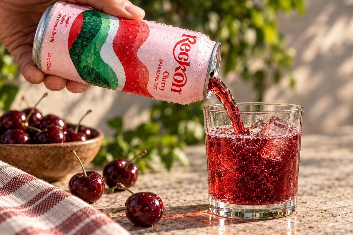 Reckon Cherry poured into a glass over ice with fresh cherries, outdoors
