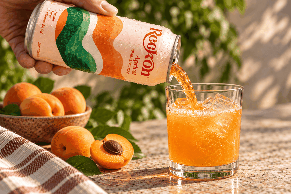 Reckon Apricot poured into a glass over ice with fresh apricots, outdoors