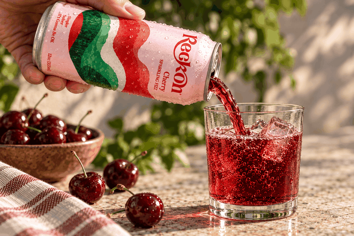 Reckon Cherry poured into a glass over ice with fresh cherries, outdoors